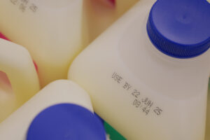 Several milk containers are clustered together, displaying use by dates.