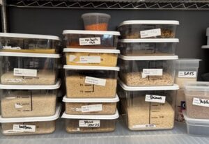 Several clear food storage containers with lids with a variety of foods in each container.