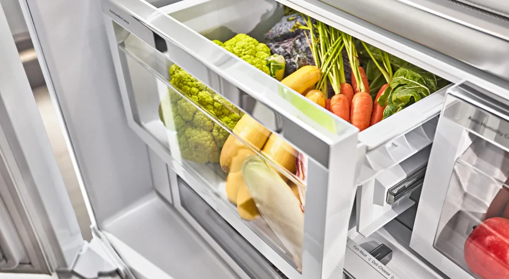 Refrigerator crisper drawer with fresh vegetables.