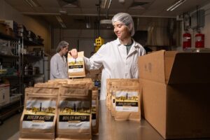 Person with hairnet holding a package of apple muffin mix