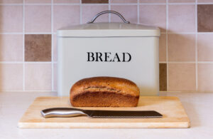 Loaf of bread on counter with knife and bread box